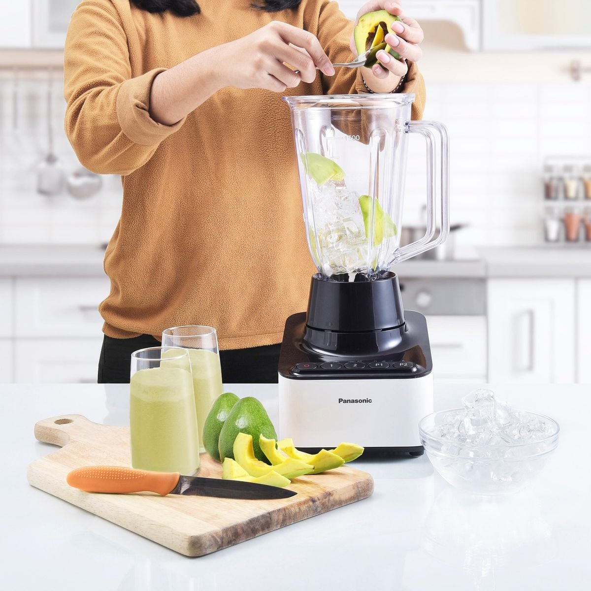 Pessoa colocando manga no liquidificador para preparar uma vitamina na cozinha