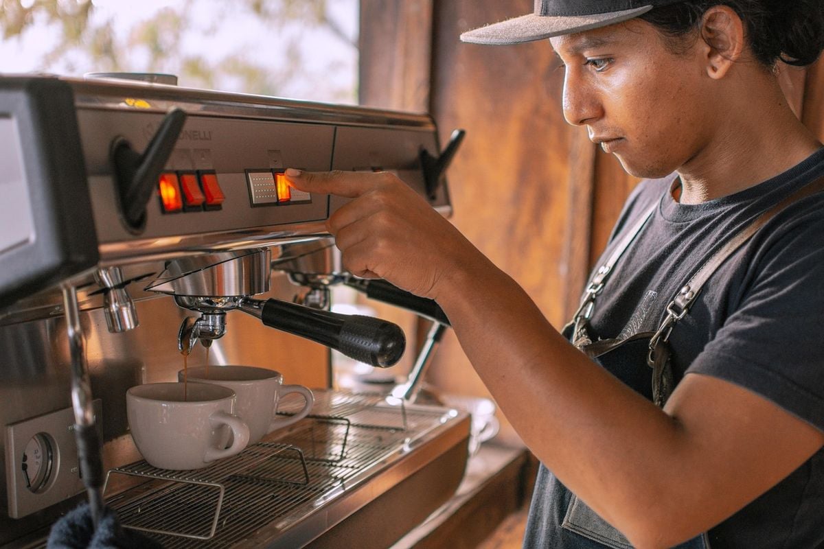 Pessoa preparando café em uma máquina profissional com duas xícaras