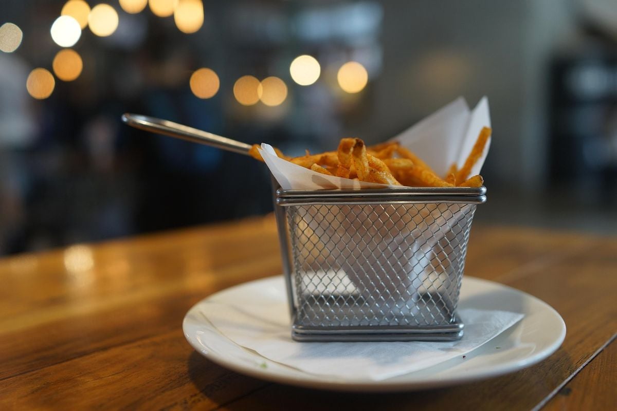 Porção de batatas fritas douradas servida em cesta metálica