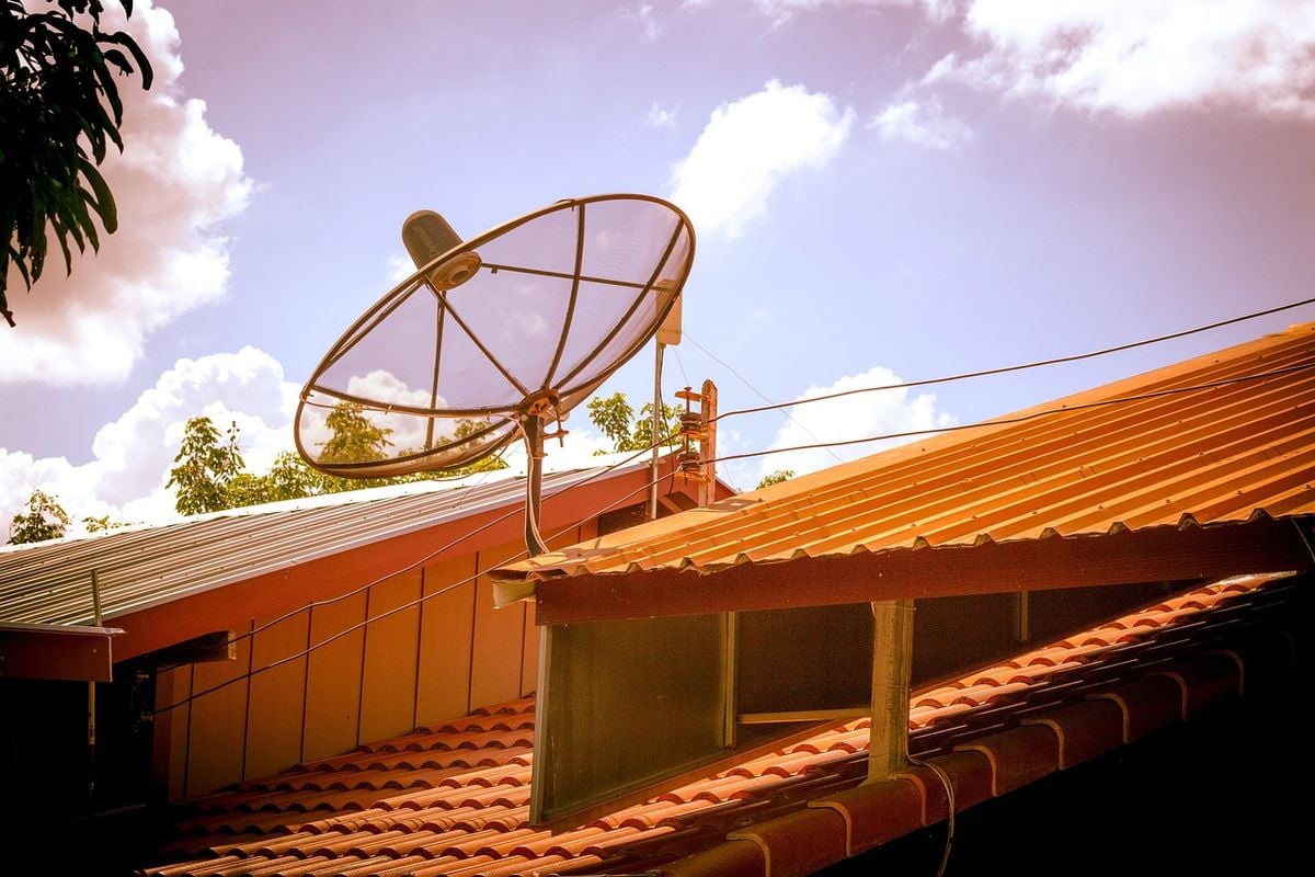 Antena parabólica instalada no telhado de uma casa contra o céu azul