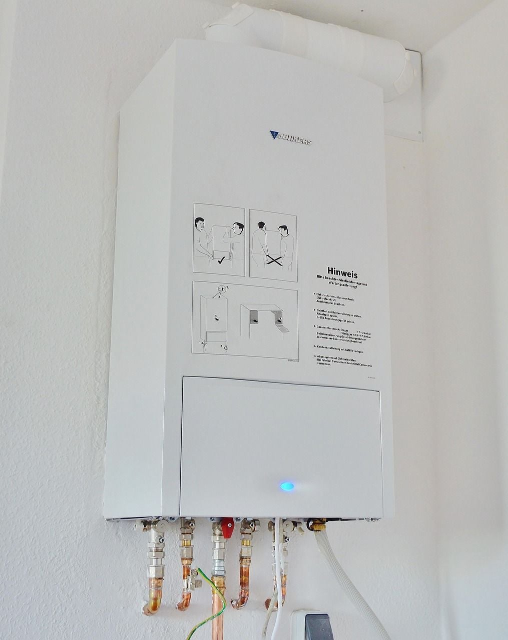 Aquecedor de água a gás instalado na parede com tubulações de água e gás