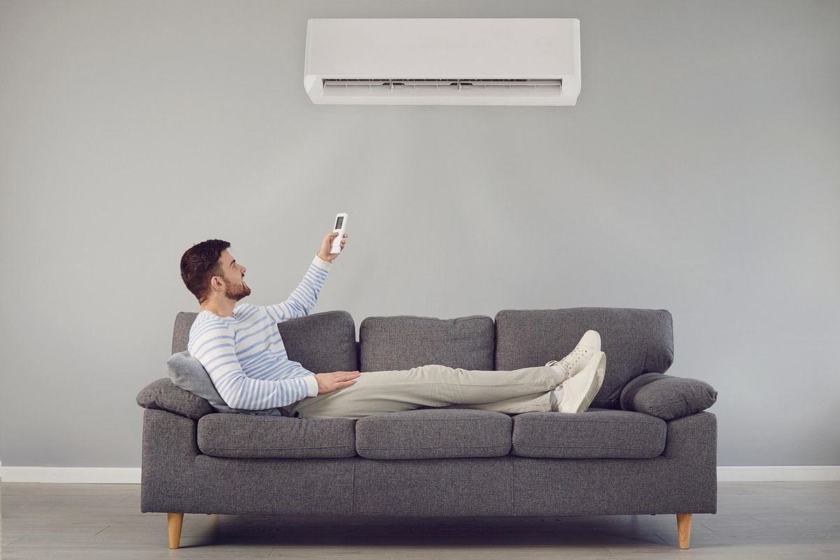 Homem no sofá usando o controle do ar-condicionado split inverter