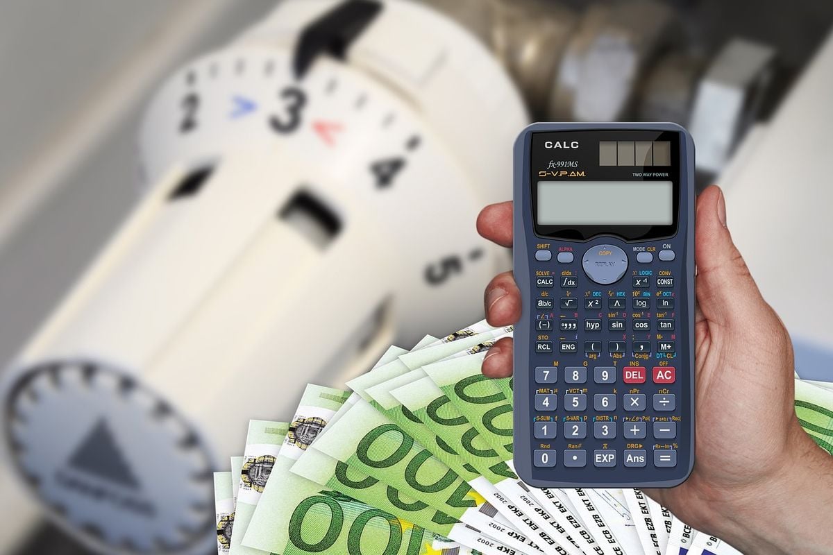 Calculadora e dinheiro diante do medidor de energia