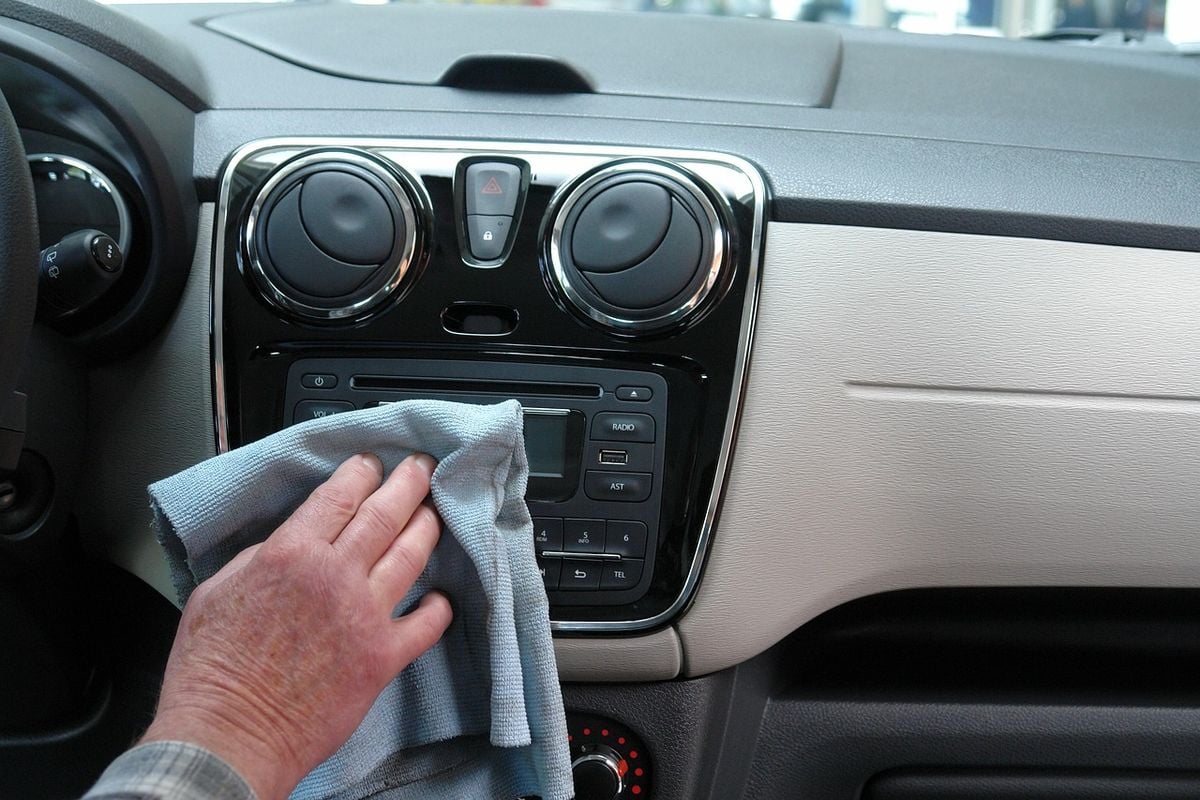 Pessoa limpando o painel do carro com pano de microfibra