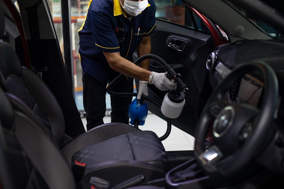 Profissional limpando o interior de um carro com equipamento de aspiração