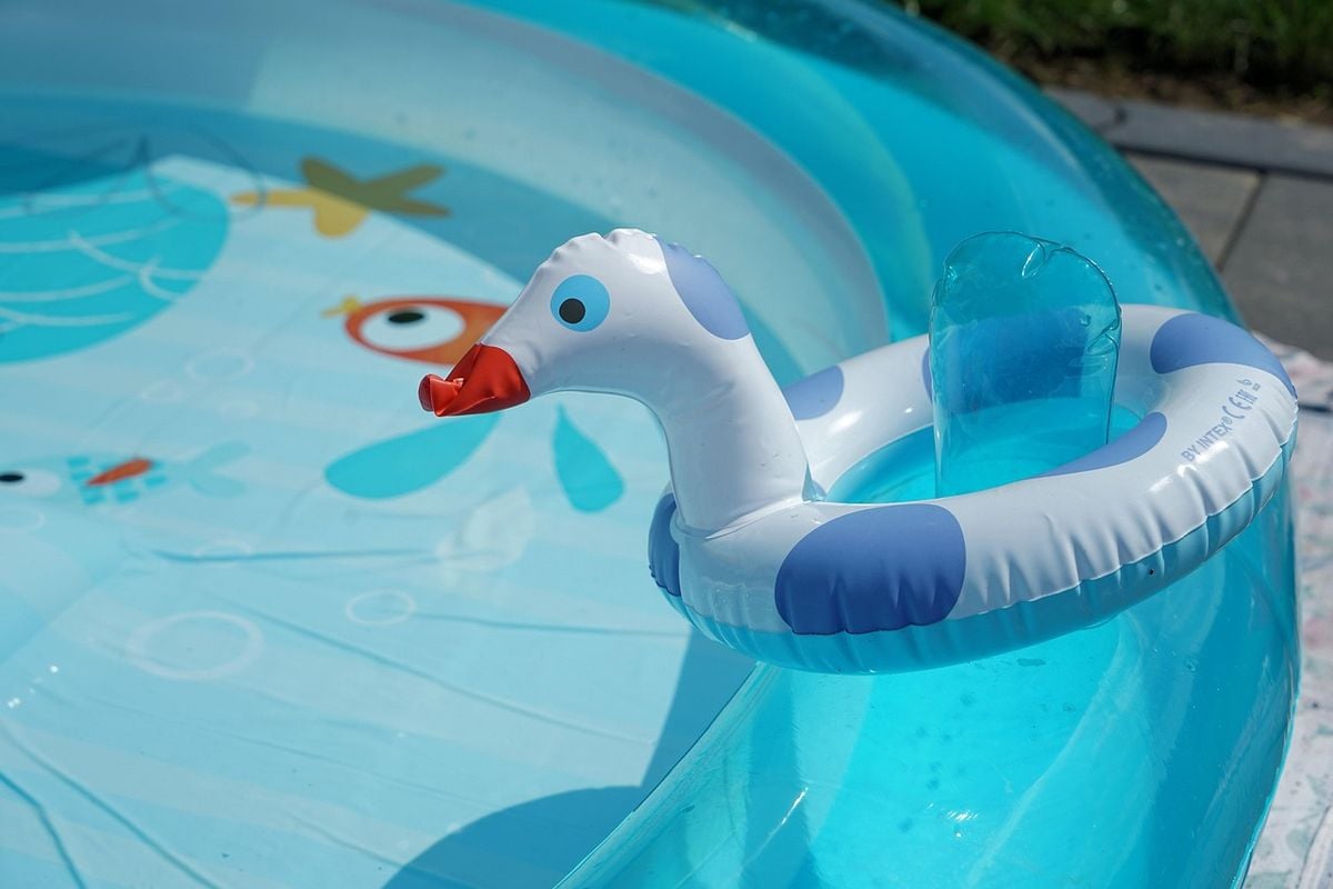 Piscina inflável de plástico azul montada no quintal com brinquedo flutuante